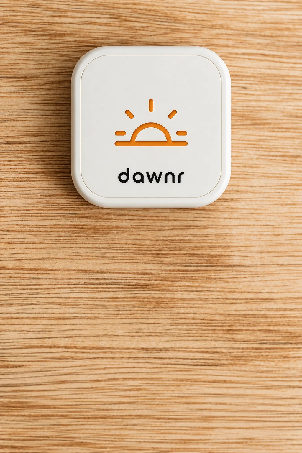 White dawnr device with its orange sunrise mark on a warm wooden table